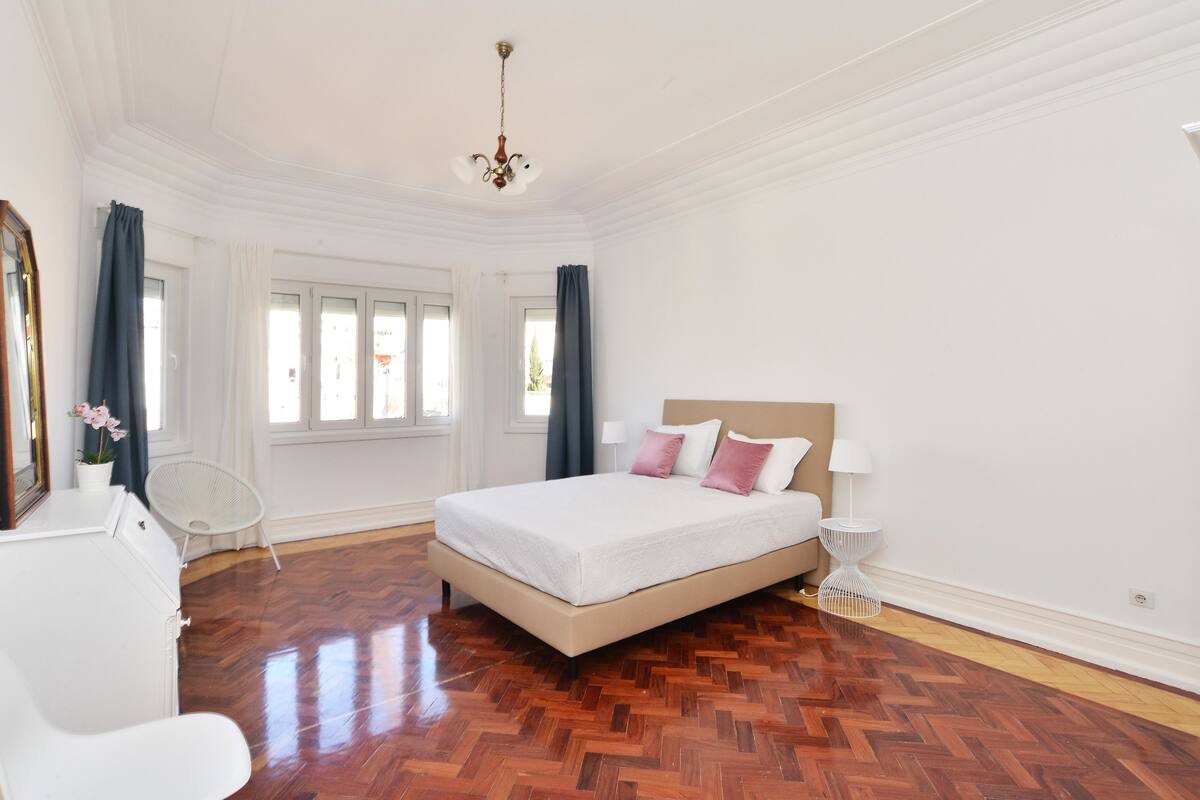 A spacious bedroom with a large bed, a chair, and a small table.