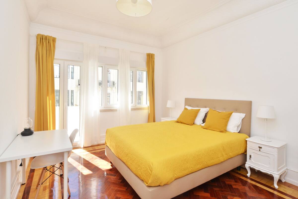 A bedroom with a large bed, a desk, and a nightstand.