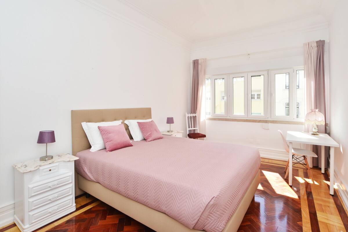 A bedroom with a bed, a desk, and a chair.