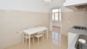 Een keuken met een witte tafel en stoelen, een gasfornuis en een raam.
