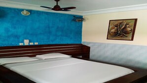 Een kamer met een houten bed, een plafondventilator en een schilderij aan de muur.