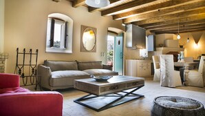 A cozy living room with a sofa, a red chair, a coffee table, and a dining area with chairs and a table. - Iconic Villas, Villa Rosa with private pool and stunning mountain view (Drakopoulata)