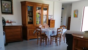 A dining area with a wooden table and chairs, a cabinet with glass doors, and a tiled floor.