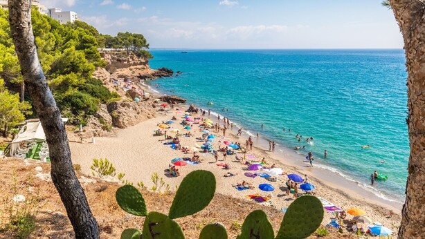 Une plage avec des gens, des parasols et une mer bleue et limpide.