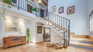 A spacious living area with a staircase, a wooden cabinet, and a dining area.