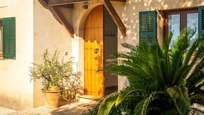 A traditional building with a wooden door, green shutters, and a stone-paved entrance.