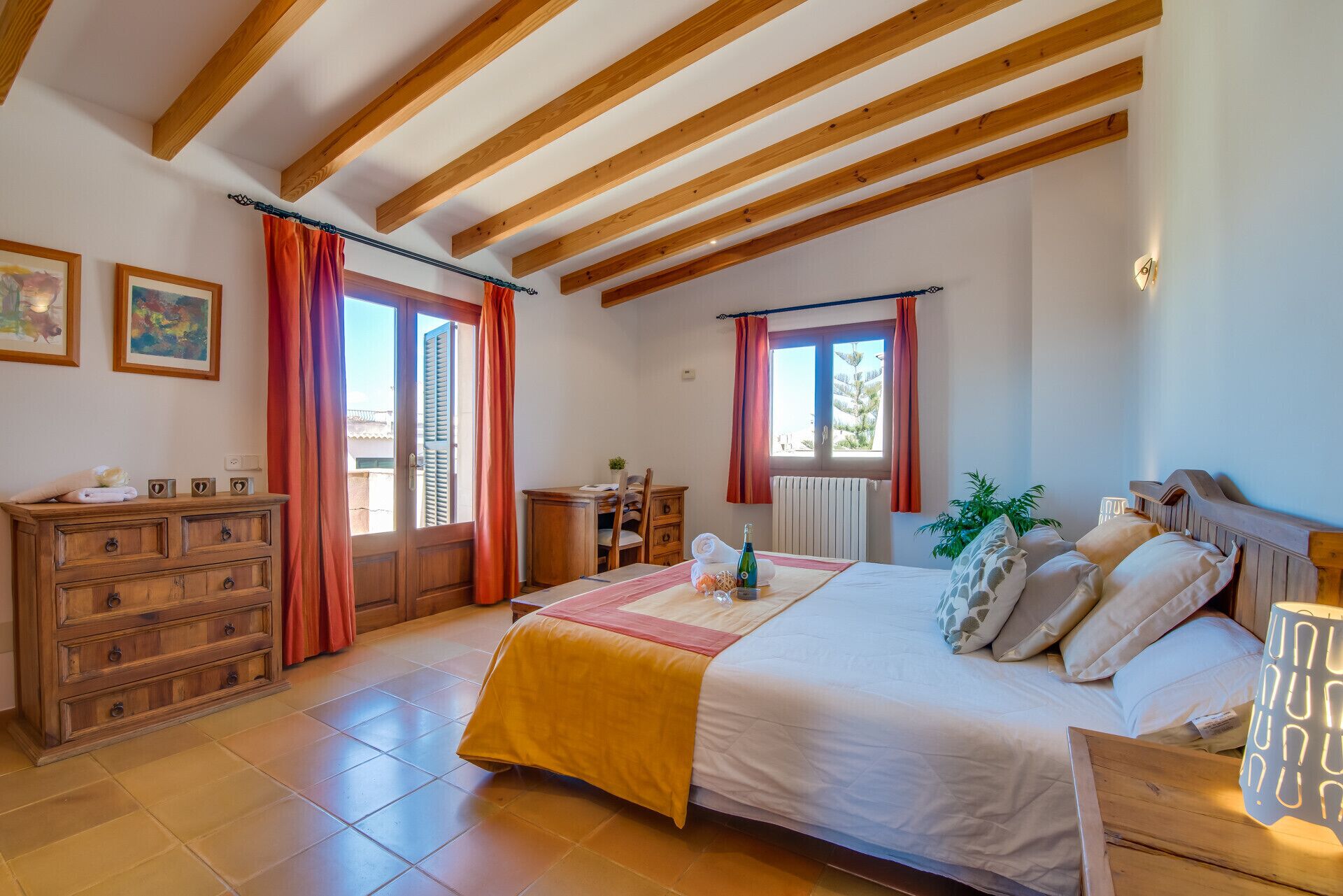 A bedroom with a wooden bed, a dresser, a window with curtains, and a view of the outside.