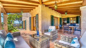An outdoor patio with wicker furniture, a grill, and a view of the surrounding landscape.