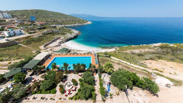 A coastal resort with a swimming pool, beach, and mountainous backdrop. - Hotel Bahamas (Sarandë)