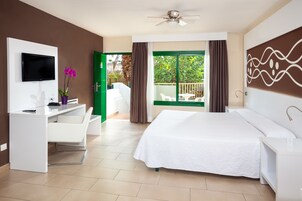 Habitación de hotel con cama, escritorio, televisor y vistas al exterior.
