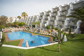 A swimming pool surrounded by lounge chairs and umbrellas, with a multi-story building in the background. - Playaolid Suites & Apartments (Adeje)