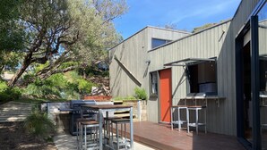 Patio esterno moderno con barbecue, posti a sedere e un pavimento in legno.