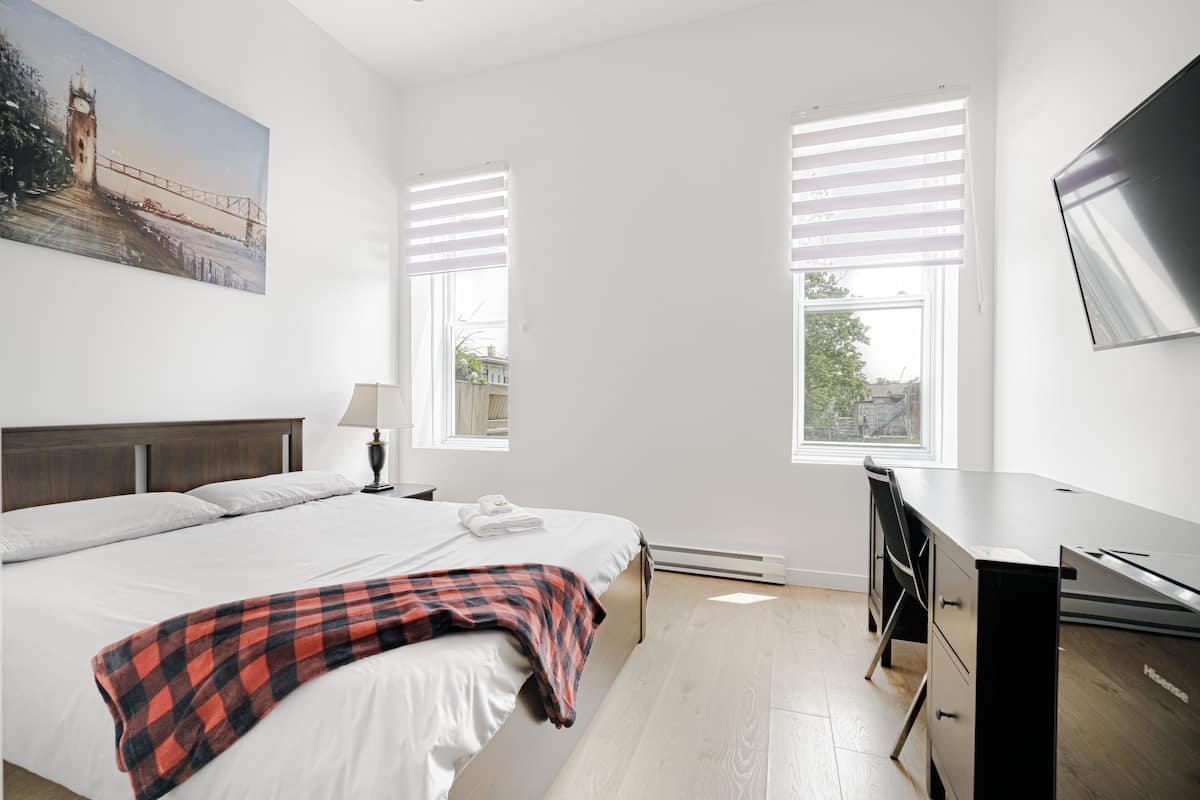 Un dormitorio con cama, escritorio y televisión.