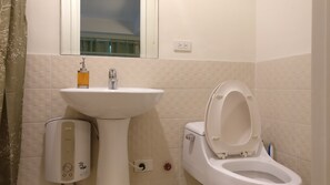 Une salle de bain avec un lavabo blanc, des toilettes et une douche.