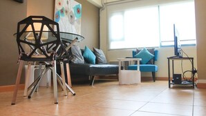 Una sala de estar moderna con un sillón negro, un sofá azul y un cuadro en la pared.