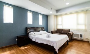 A bedroom with a bed, bedside tables, a chair, and a window. - Embrace Place (Taguig)