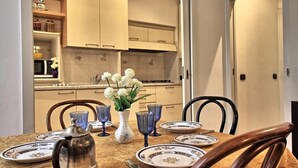 A dining area with a table set for four, featuring blue glassware, white plates, and a vase with flowers. - Logicasa Residenza Como Centro (Como)