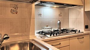 A kitchen with a stainless steel sink, a gas stove, and a range hood. - Logicasa Residenza Como Centro (Como)