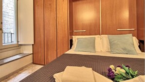 A bedroom with a bed, wooden wardrobe, and a window. - Logicasa Residenza Como Centro (Como)