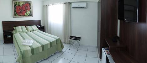 Una habitación de hotel con cama, televisor, escritorio y silla.