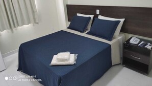A hotel room with a bed, a nightstand, and an air conditioning unit. - Hotel Rametta (Montes Claros)