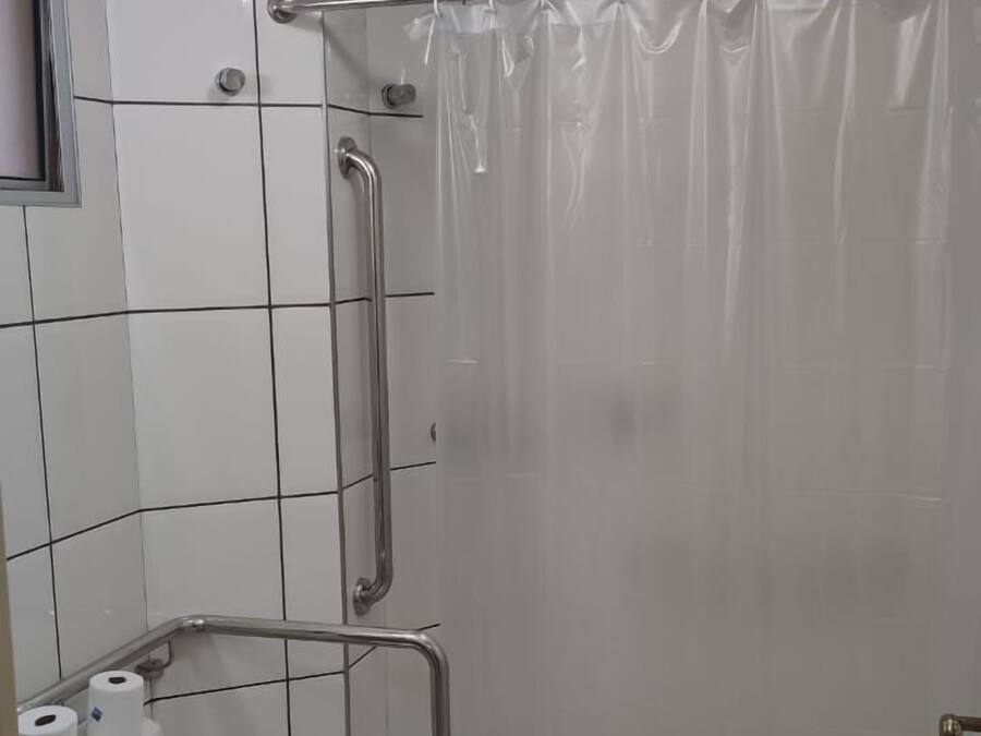 Un baño pequeño y moderno con inodoro, ducha con puerta de cristal y barandilla.