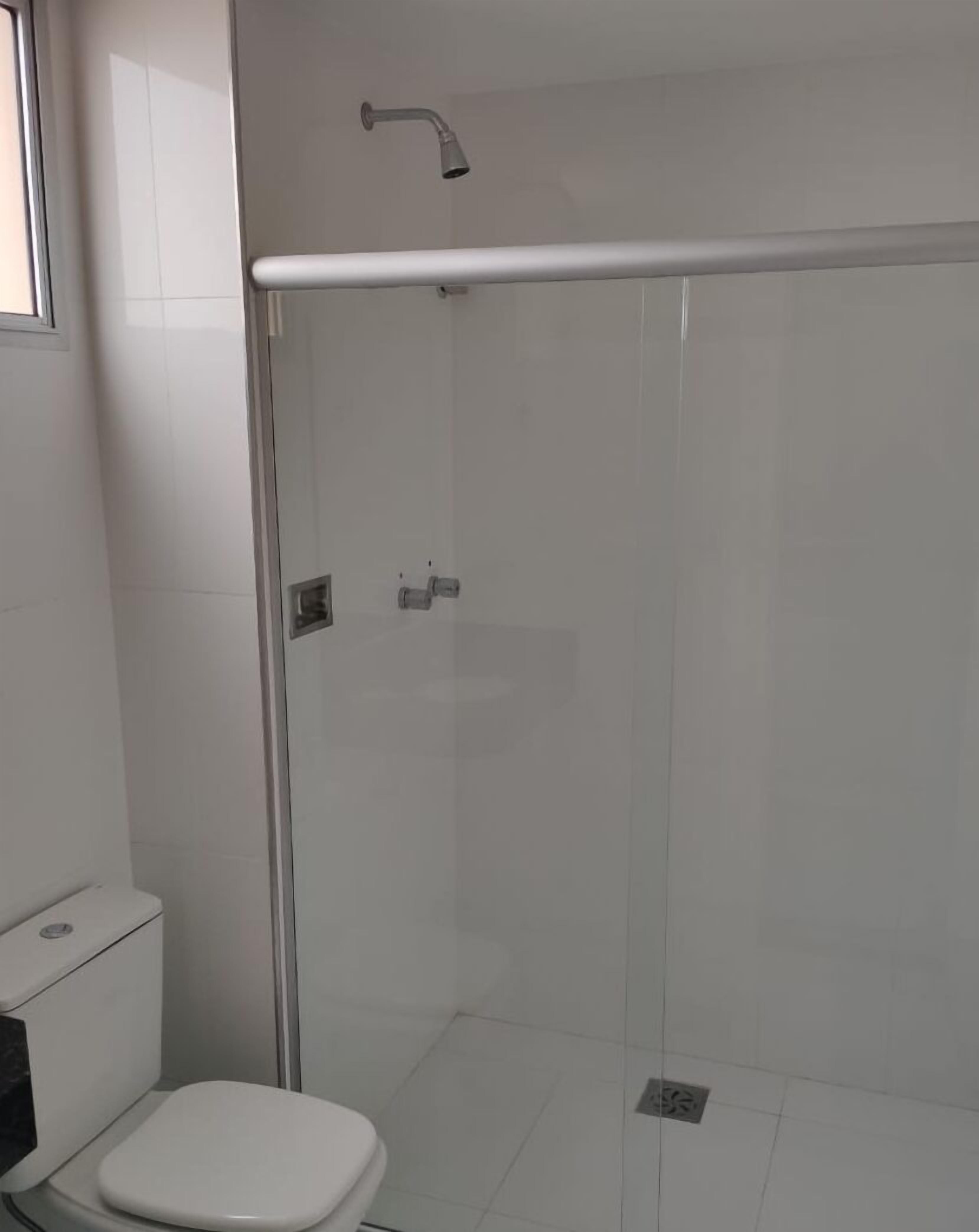 A modern bathroom with a glass-enclosed shower, a white toilet, and a marble countertop.