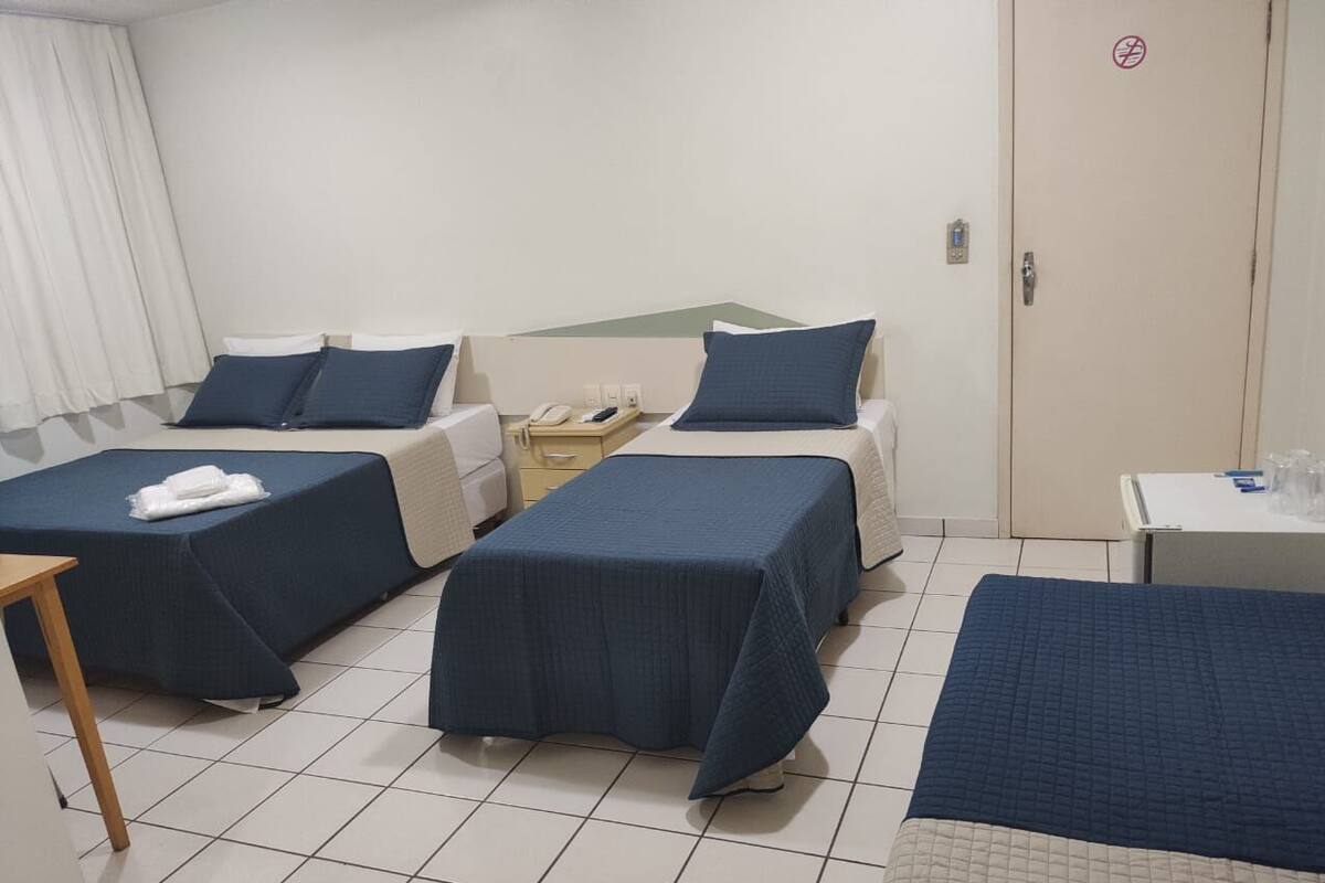 A hotel room with two single beds, a small table, a telephone, and a door with a lock.
