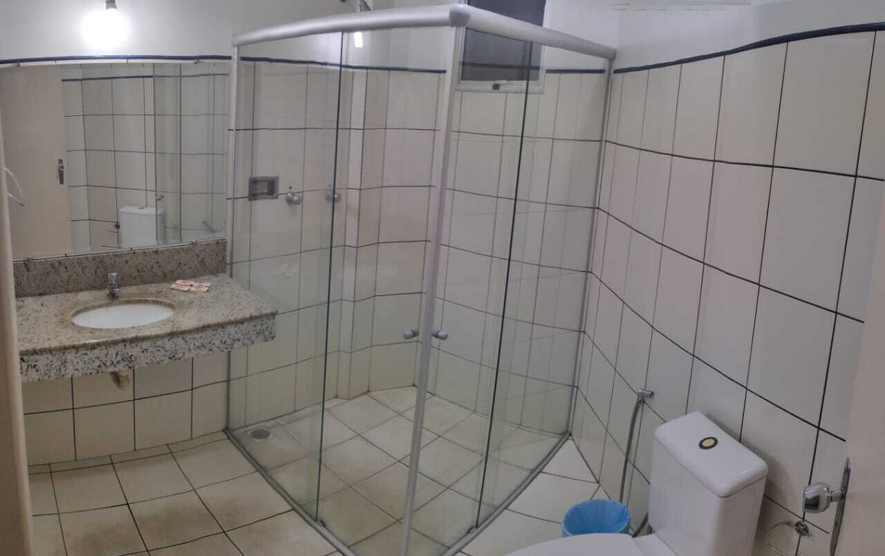 Un baño con ducha envuelta en vidrio, un lavamanos y un inodoro.