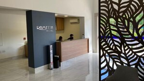 A reception area with a modern design, including a reception desk, a black pillar with the hotel name, and a decorative partition with a leaf pattern. - Hotel Rametta (Montes Claros)