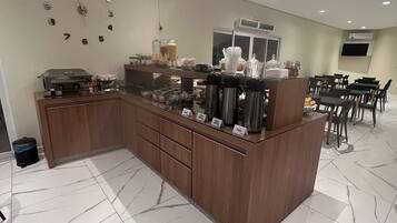 A modern kitchen area with a marble floor, wooden cabinets, and a coffee station with various appliances and containers.