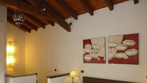 Un dormitorio con una cama, una mesita de noche, una lámpara y dos cuadros colgados en la pared.