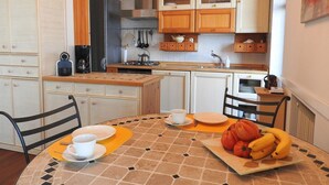 Una cocina compacta con armarios de madera, una estufa a gas y una zona de comedor con una mesa dispuesta para dos personas.