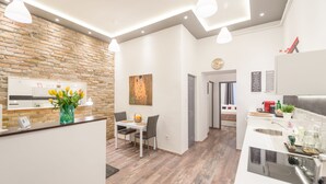 Eine moderne Küche mit Backsteinwand, weißen Arbeitsplatten und Pendelleuchten.