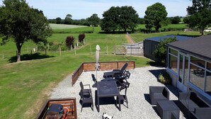 A patio area with outdoor furniture, a barbecue grill, and a view of a green field and trees. - LE JARRIER DETACHED HOLIDAY RENTAL - ALPES MANCELLES -PRIVATE  POOL -FIBER WIFI (Saint-Georges-le-Gaultier)