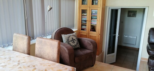 Ein Hotelzimmer mit einer braunen Ledersofa, einer gemusterten Tischdecke, einem Bücherregal und einer Tür zu einem weiteren Zimmer.