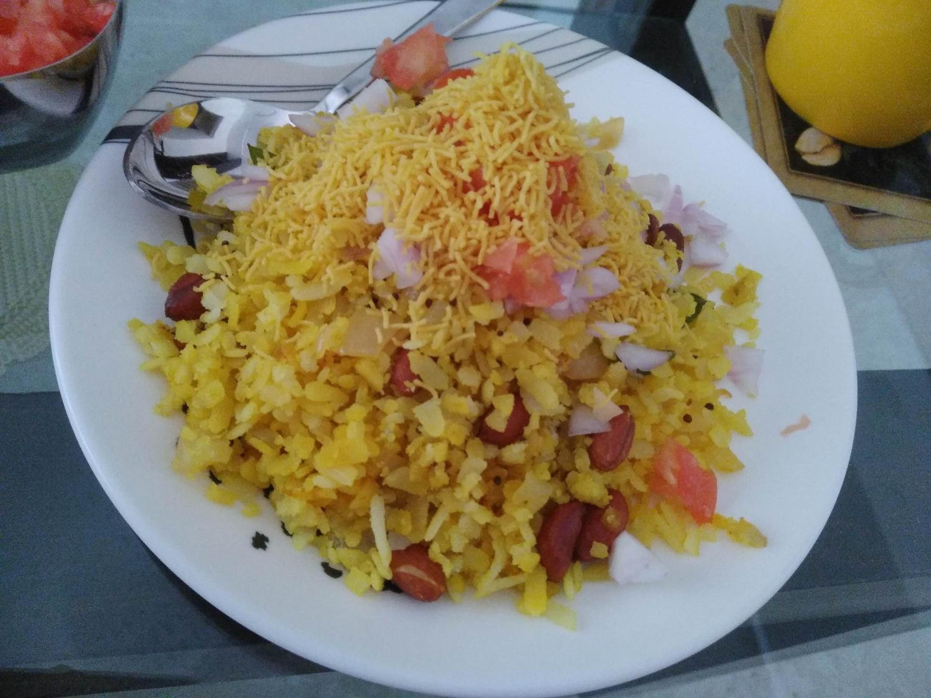 A plate of food with yellow rice, tomatoes, onions, and shredded cheese.