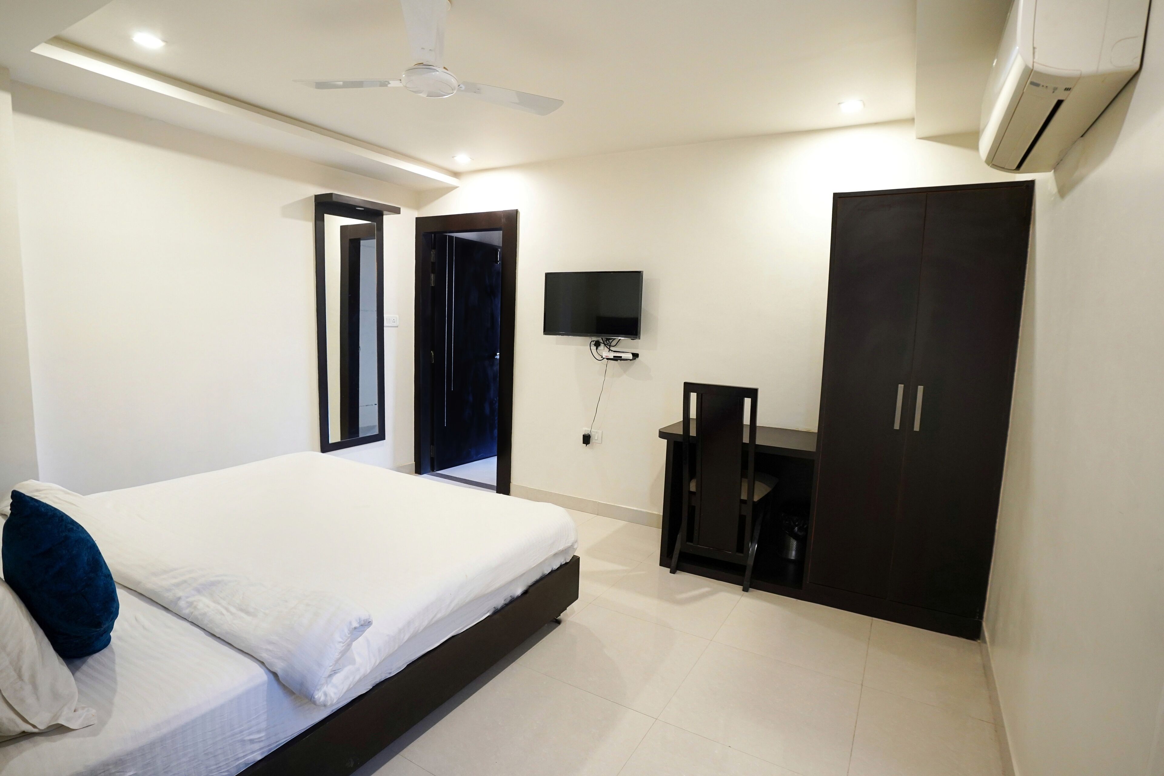 Un dormitorio con cama, escritorio, armario, televisor y aire acondicionado.