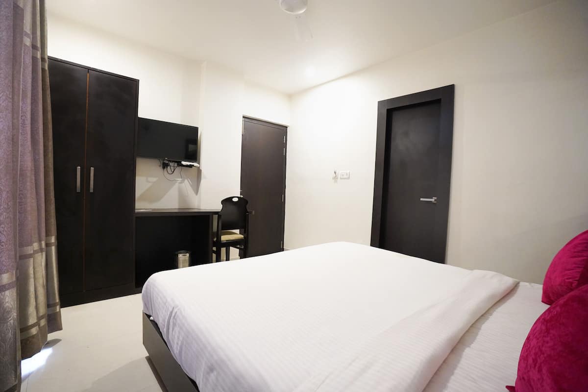 A bedroom with a bed, a desk, and two wardrobes.