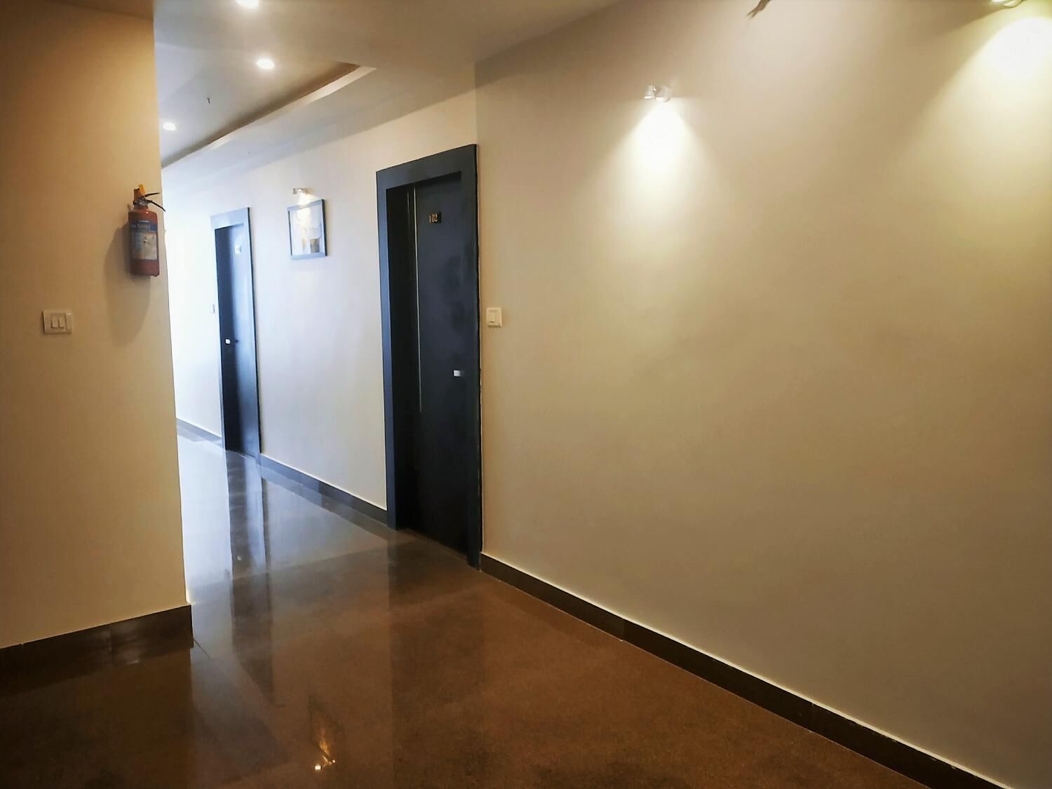 A hallway with a fire extinguisher, two doors, and a light fixture on the wall.