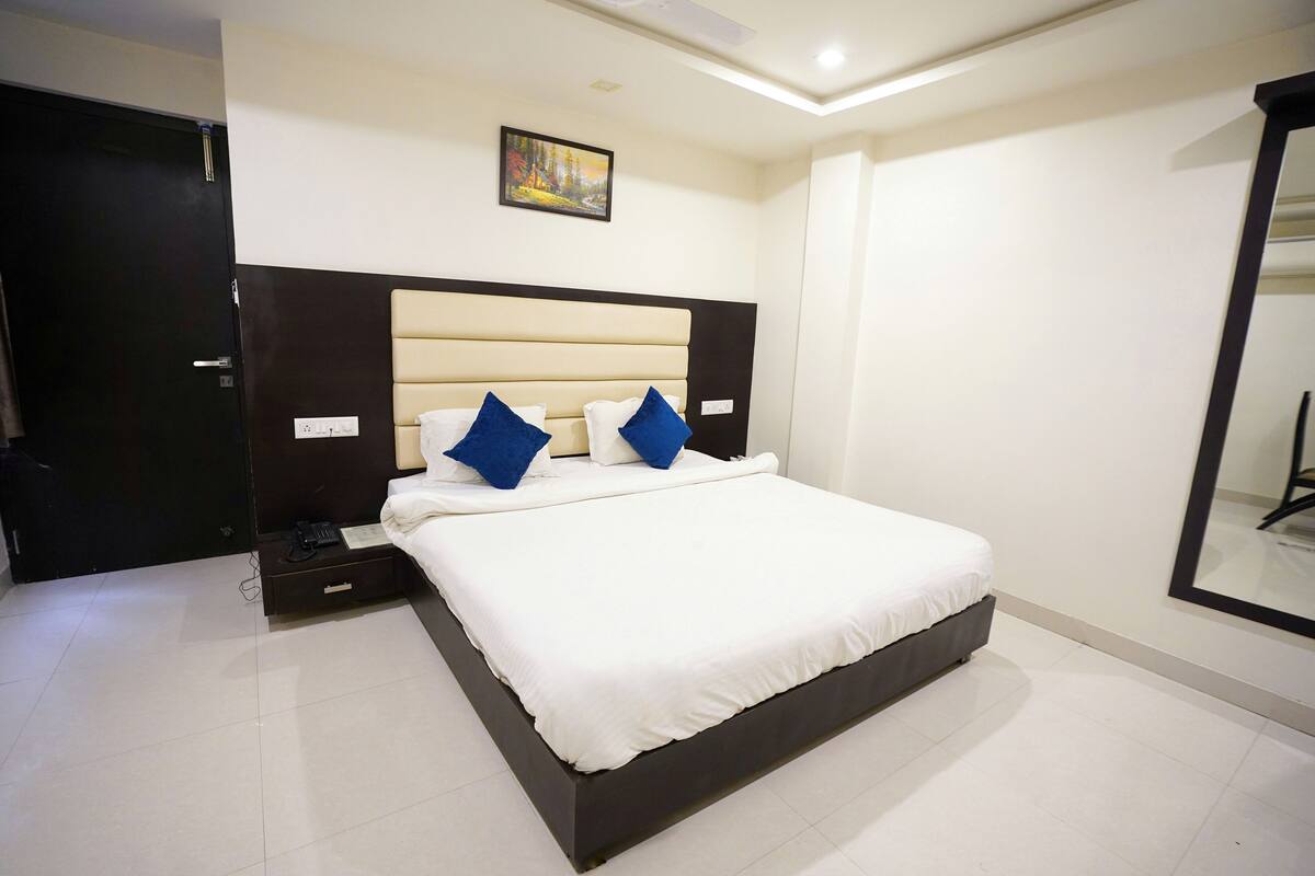 A modern hotel room with a large bed, a nightstand, and a painting on the wall.