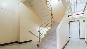 A clean, modern stairwell with a metal handrail and white walls. - RedDoorz Plus @ RSG SS Residens Vito Cruz (Manila)