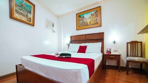 A neatly made bed with a red blanket, a wooden headboard, and a nightstand with a lamp. - RedDoorz @ La Casa Guesthouse (Angeles City)