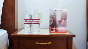 A wooden nightstand with two RedDoorz water bottles and a promotional sign. - RedDoorz @ La Casa Guesthouse (Angeles City)