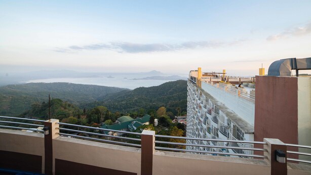 A high-rise building with a view of a valley and a body of water. - RedDoorz Premium @ Cityland Tagaytay 2 (Tagaytay)