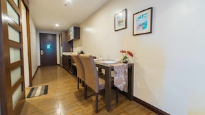 A hallway with wooden flooring, a dining table with chairs, and a door with frosted glass panels. - RedDoorz Premium @ West Avenue Quezon City (Quezon City)