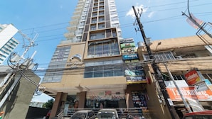A multi-story building with various commercial establishments on the ground floor, including a frozen yogurt shop and a convenience store. - RedDoorz Premium @ West Avenue Quezon City (Quezon City)