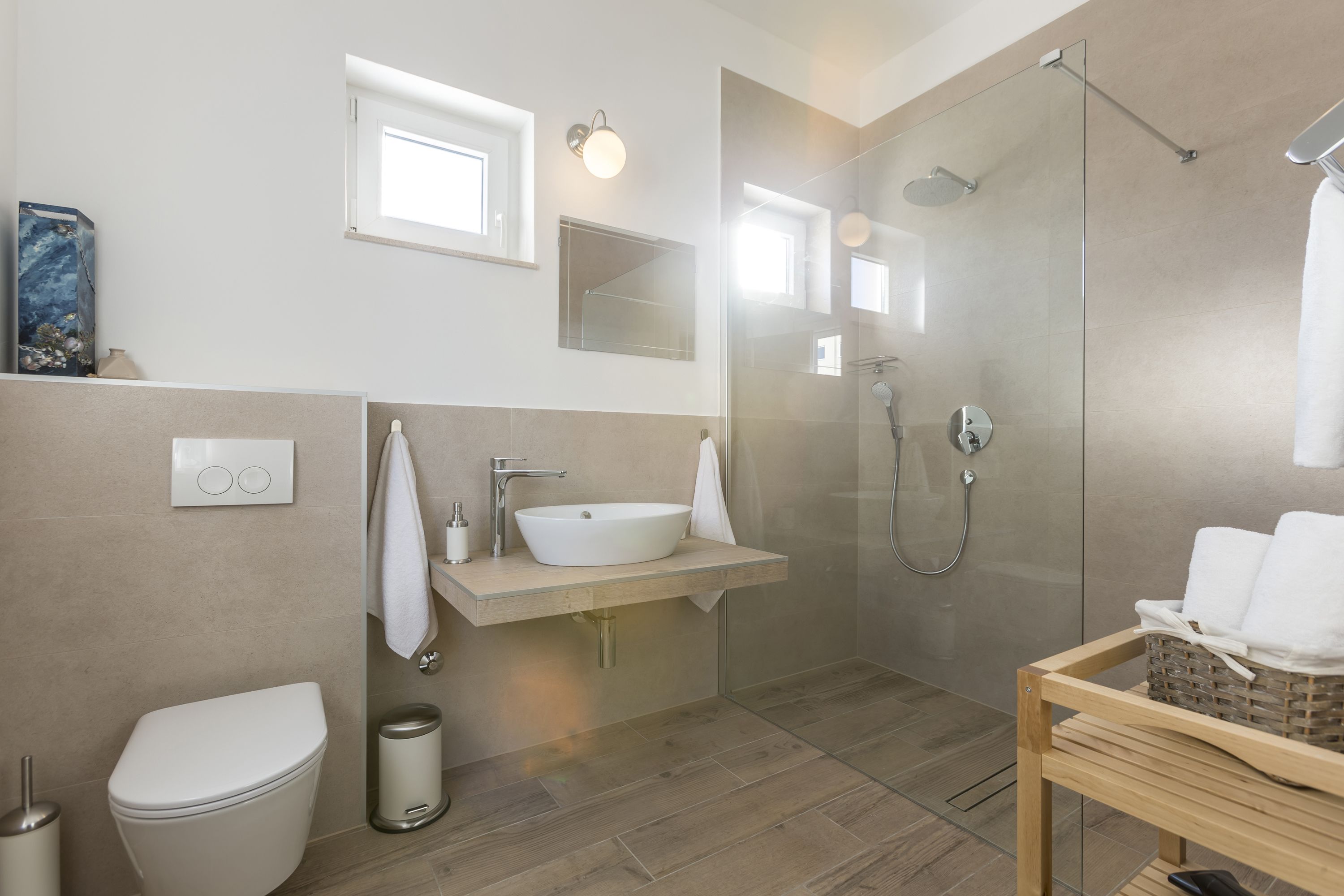 Un baño moderno con ducha de vidrio, lavamanos blanco y un inodoro.