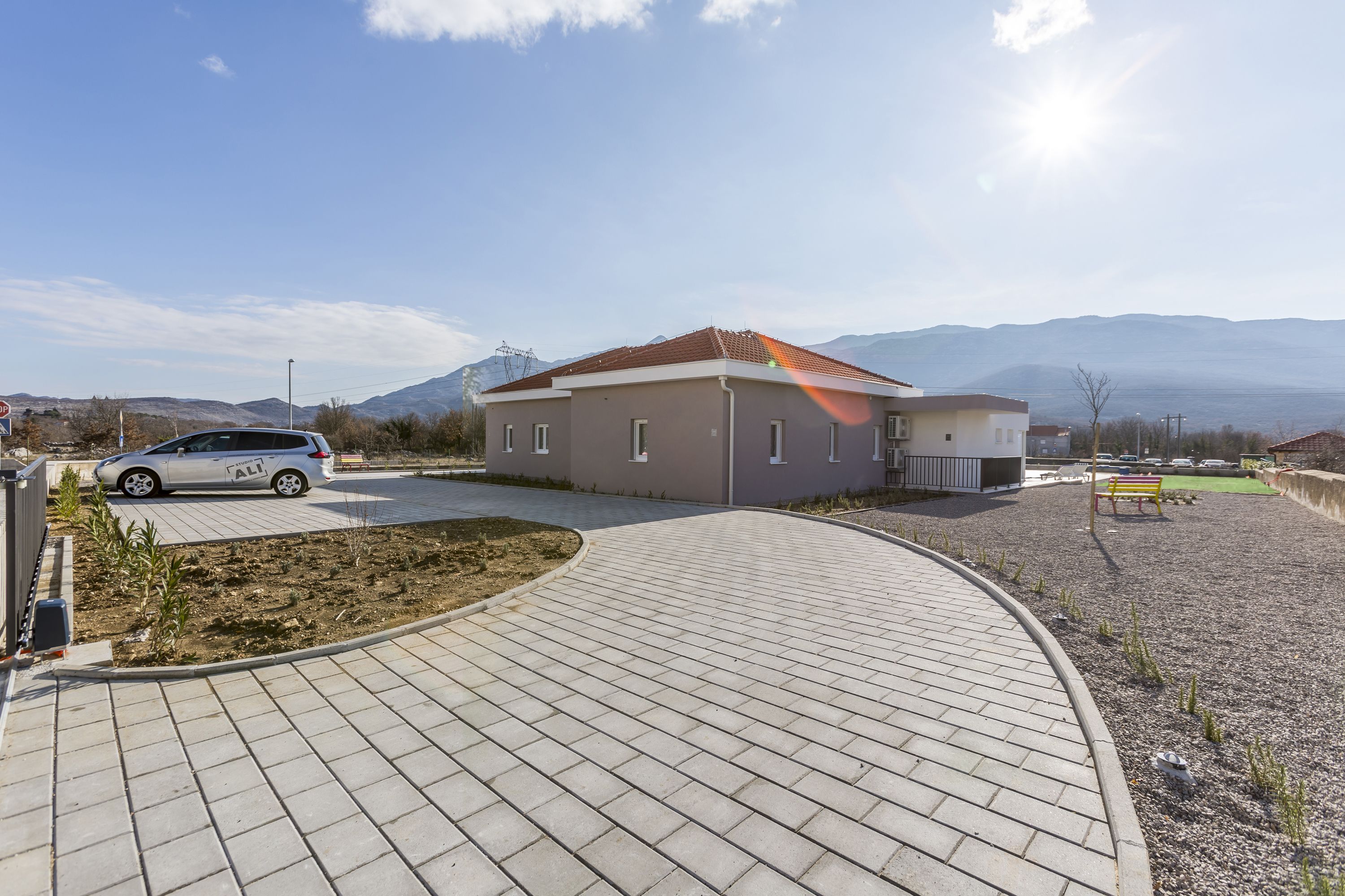 Un edificio moderno con vialetto lastricato e un'auto parcheggiata.