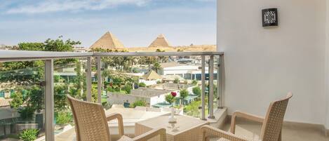 A balcony with wicker furniture and a clear view of the pyramids.
